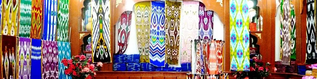 Rolls and hanging lengths of brightly patterned ikat silk in a shop.