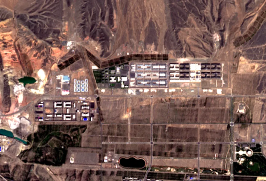 The same ground four years later: a built strip about 2 km long, divided into blocks of rows of long identical buildings, and a second, separate group of the same buildings inside its own boundary about 1.6 km to the west.